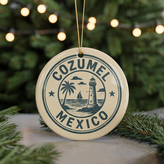 A circular ornament with the text "COZUMEL MEXICO" and a lighthouse illustration, hanging from a string against a background of Christmas lights and greenery.