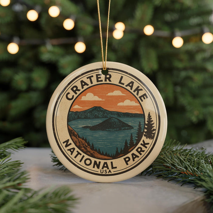 A circular ornament with the text "CRATER LAKE NATIONAL PARK USA" and an illustration of a lake surrounded by mountains and pine trees.