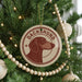 A Christmas tree decorated with ornaments, including a circular ornament with a dachshund dog image and the word "DACHSHUND" written on it.
