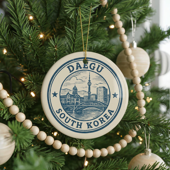 A Christmas tree decorated with ornaments, including a circular ornament with a cityscape and text, surrounded by lights and greenery.