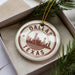 A circular ornament with the text "DALLAS TEXAS" printed on it, surrounded by a border and a star.