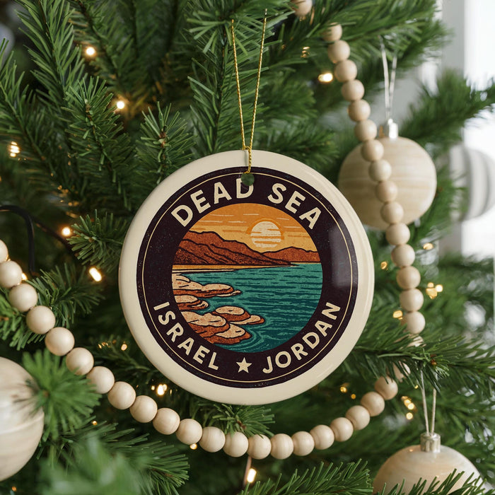 A circular ornament on a Christmas tree, featuring a scenic image of the Dead Sea and Israel.