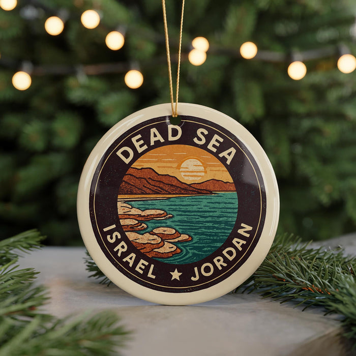 A circular ornament with a design depicting a beach and mountains, surrounded by the text "DEAD SEA ISRAEL" and "JORDAN".