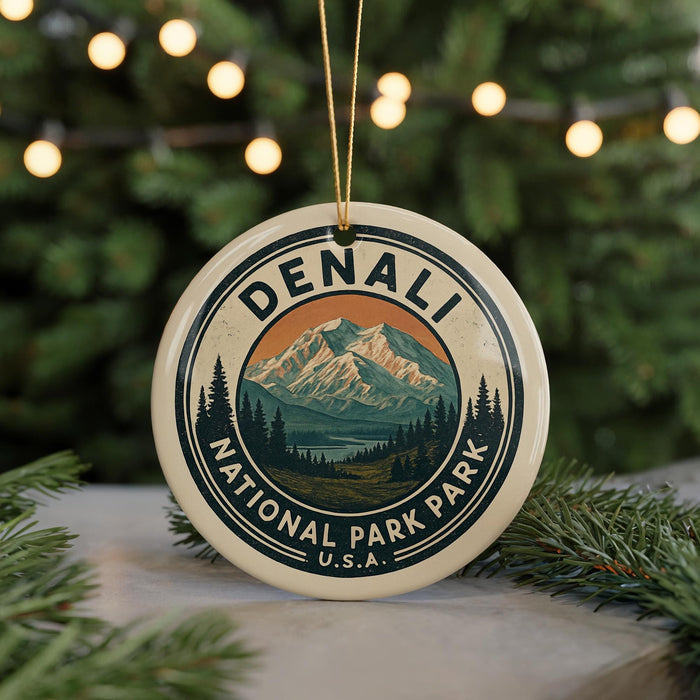 A decorative ornament featuring the name "DENALI" and the text "NATIONAL PARK PARK U.S.A." in a circular design, with a mountain landscape and pine trees in the center.