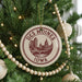A Christmas tree decorated with ornaments, including a circular ornament with the text "DES MOINES IOWA" and a cityscape design.