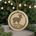 A round ornament featuring a deer with horns, hanging from a string.