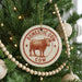 A Christmas tree decorated with ornaments, including a circular ornament with a cow illustration and the text "DOMESTIC COW" and "COW" printed on it.