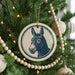 A Christmas tree decorated with ornaments, including a circular ornament featuring a donkey's head.