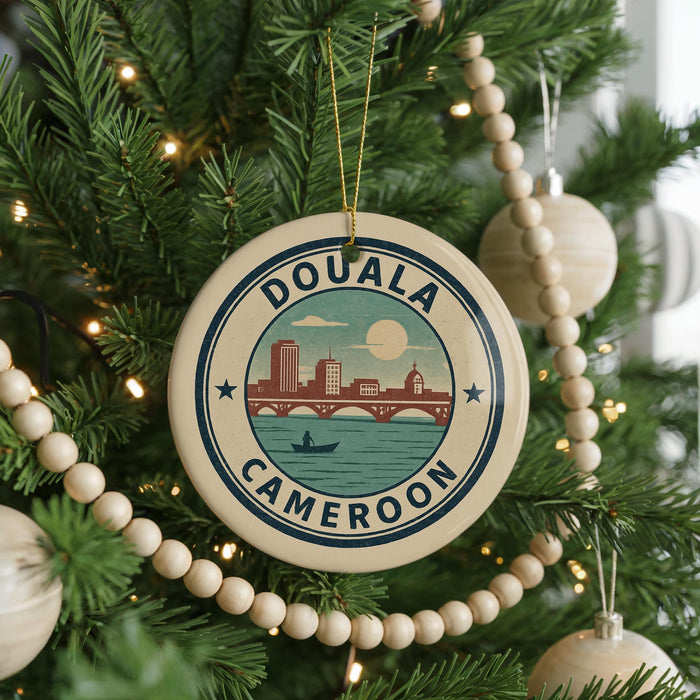 A circular ornament on a Christmas tree, featuring a cityscape and a boat, with the text "DOUALA CAMERON" around the edge.