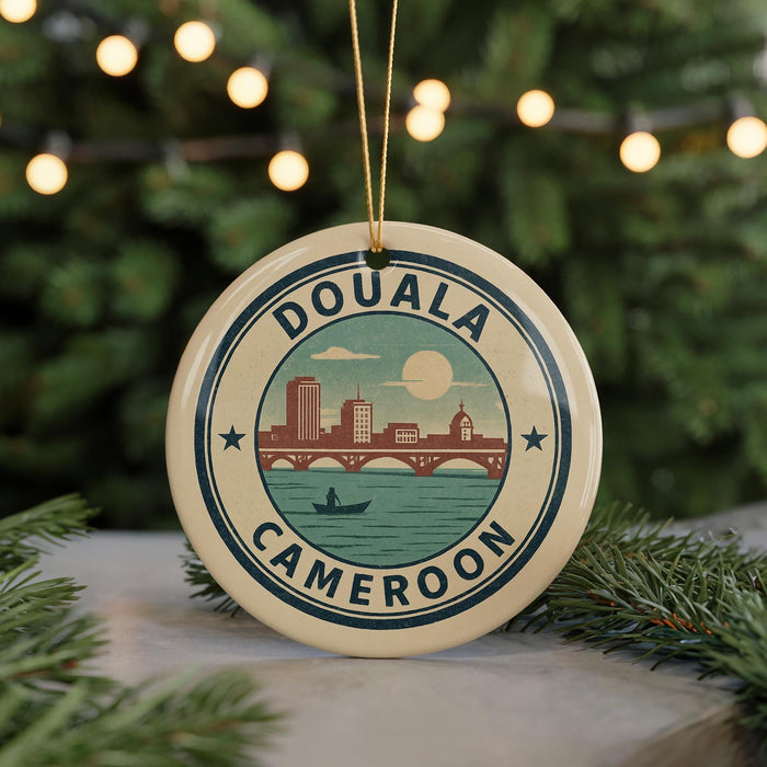 A circular ornament with the text "DOUALA CAMERON" and an illustration of a cityscape with a river and bridge.