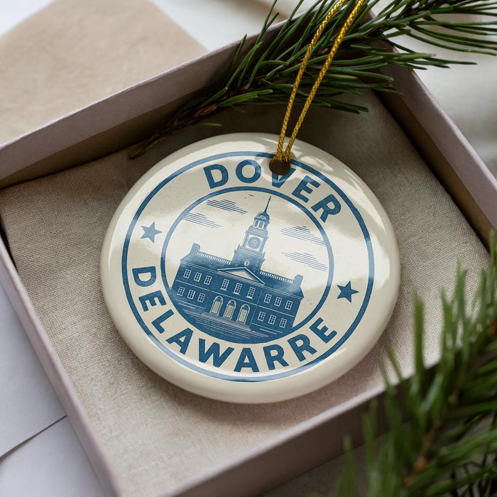 A decorative ornament in a box, featuring a blue and white design with a building and the text "Dover Delaware".