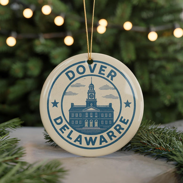 A round ornament with the text "Dover Delawarre" and a graphic of a building, hanging from a string against a background of Christmas lights and greenery.