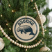 A Christmas tree decorated with ornaments, including a circular ornament with a manatee and the word "Dugong" written on it.