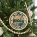 A Christmas tree decorated with ornaments, including a circular ornament with the text "DURBAN SOUTH AFRICA" and a beach scene.