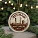 A circular ornament with the text "DURHAM NORTH CAROLINA USA" printed on it, featuring a silhouette of a city skyline.
