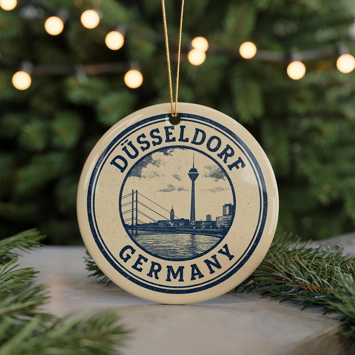 A circular ornament with the text "DÜSSELDORF GERMANY" and an illustration of a city skyline, hanging from a string.