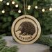 A round ornament with a black and white illustration of an echidna, and the word "ECHIDNA" written below it, is hanging from a string.