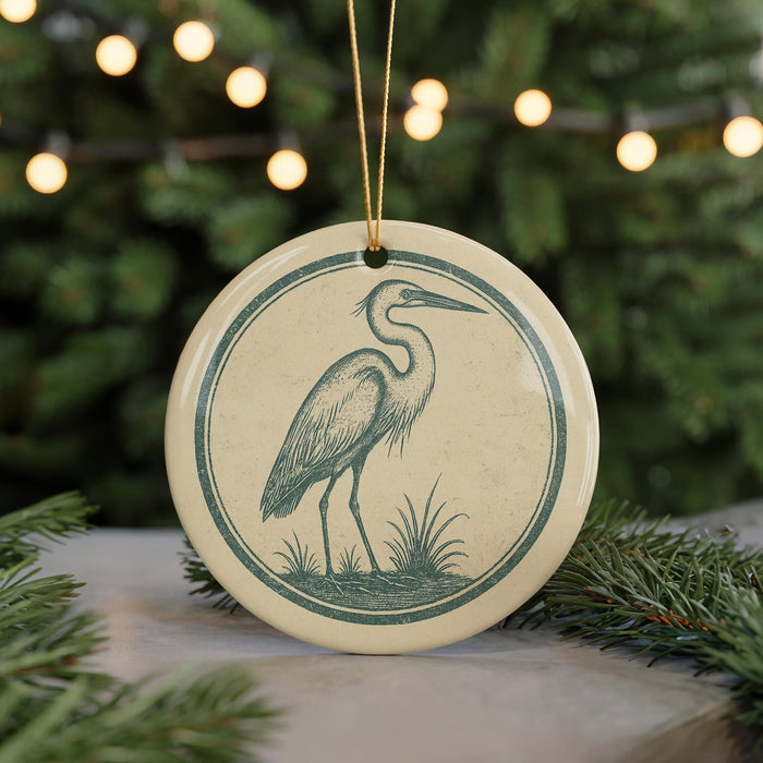 A ceramic ornament featuring a heron standing on grass, with a string of lights in the background.
