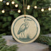 A ceramic ornament featuring a heron standing on grass, with a string of lights in the background.