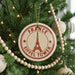 A Christmas tree decorated with ornaments, including a circular ornament with the Eiffel Tower and the text "FRANCE EIFFLÉT TOWER" on it.