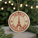 A circular ornament with the Eiffel Tower and the text "FRANCE" printed on it, hanging from a string.