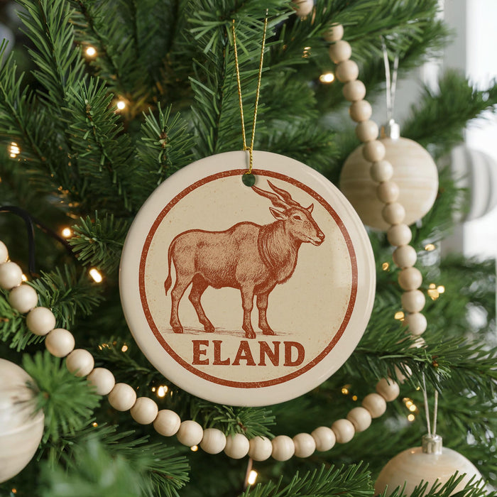 A Christmas tree decorated with ornaments, including a circular ornament with a picture of a brown animal and the word "ELAND" written on it.