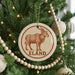 A Christmas tree decorated with ornaments, including a circular ornament with a picture of a brown animal and the word "ELAND" written on it.