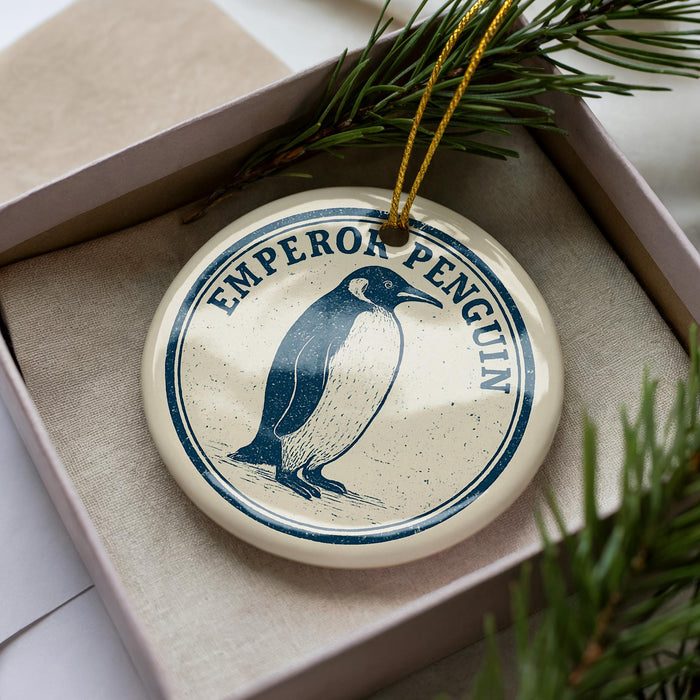 A round ornament with a penguin image and the word "EMPOROR PENGUIN" printed on it, hanging from a string.
