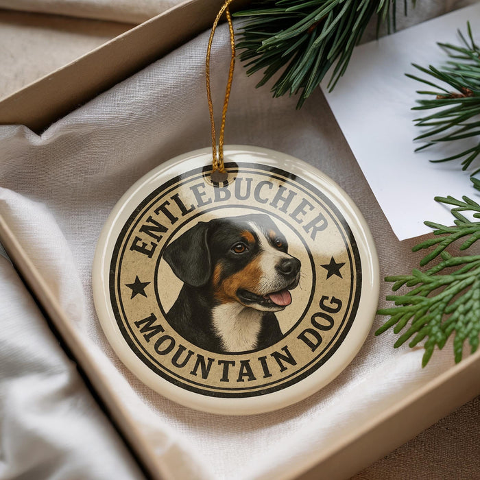 A round ornament featuring a dog's head and the text "ENTLEBUCER MOUNTAIN DOG" is displayed in a box with pine branches.