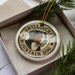 A circular ornament with a dog image and the text "ENTLEBUCHER MOUNTAIN DOG" printed on it, placed inside a box with pine branches.