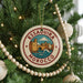 A circular ornament on a Christmas tree, featuring a graphic of a cityscape with a castle and a castle surrounded by water.