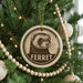 A Christmas tree decorated with ornaments, including a round ornament with a ferret image and the word "FERRET" written on it.