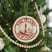A Christmas tree decorated with ornaments, including a circular ornament with the text "FIRE ISLAND NEW YORK" and a lighthouse image.