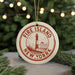 A circular ornament with the text "FIRE ISLAND NEW YORK" and a lighthouse illustration, hanging from a string.