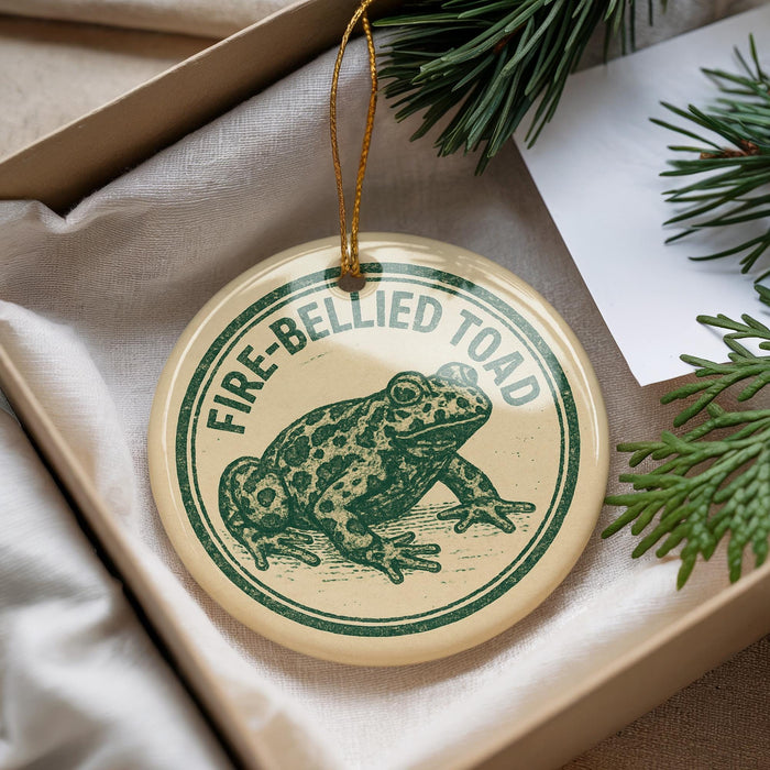 A round ornament with a green frog image and the text "FIRE-BELLIED TOAD" printed on it, hanging from a string.