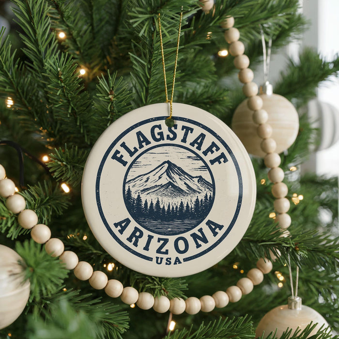 A Christmas tree decorated with ornaments, including a circular ornament with the text "Flagstaff Arizona USA" and a mountain illustration.