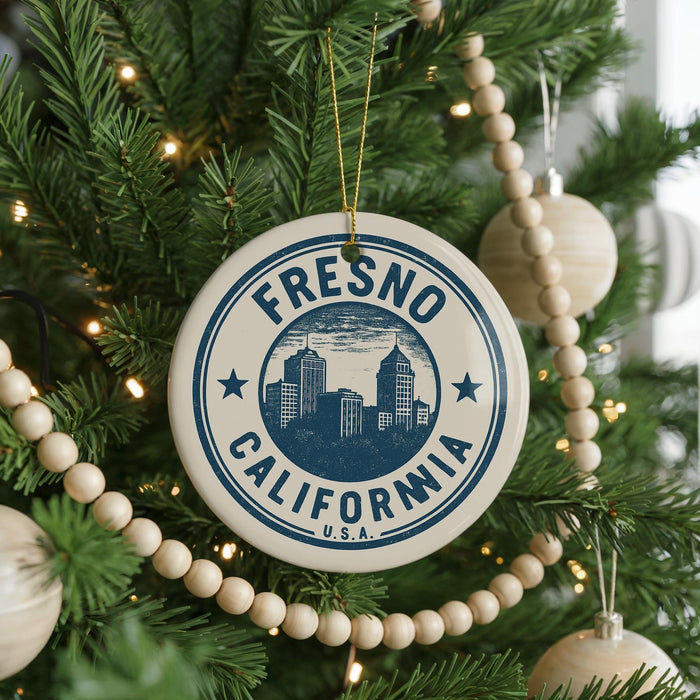 A close-up of a Christmas tree decorated with ornaments, including a circular ornament with the text "FRESNO CALIFORNIA" and a city skyline image.