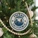 A close-up of a Christmas tree decorated with ornaments, including a circular ornament with the text "FRESNO CALIFORNIA" and a city skyline image.