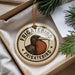 A circular ornament with the text "FRIGATEBIRD" and an illustration of a bird is displayed in a box with pine branches.