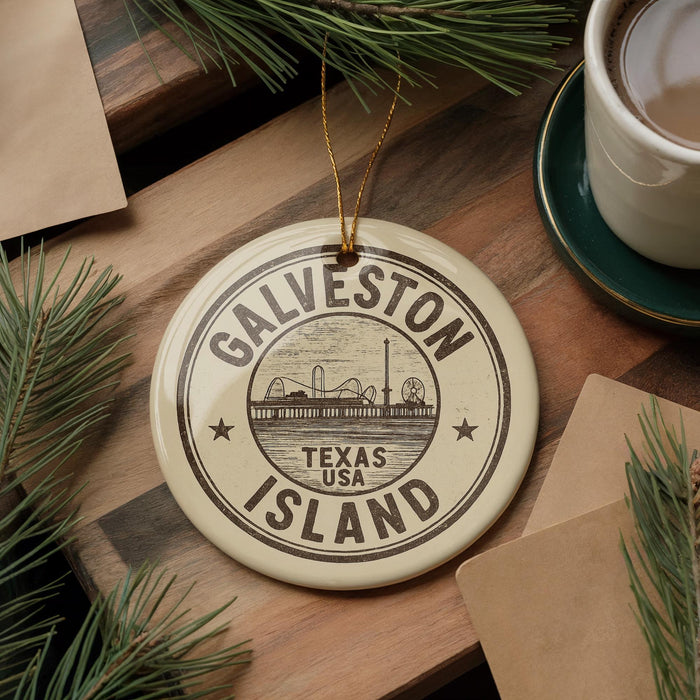 A circular ornament with the text "GALVESTON TEXAS ISLAND" printed on it, surrounded by pine branches and a cup of coffee on a wooden surface.