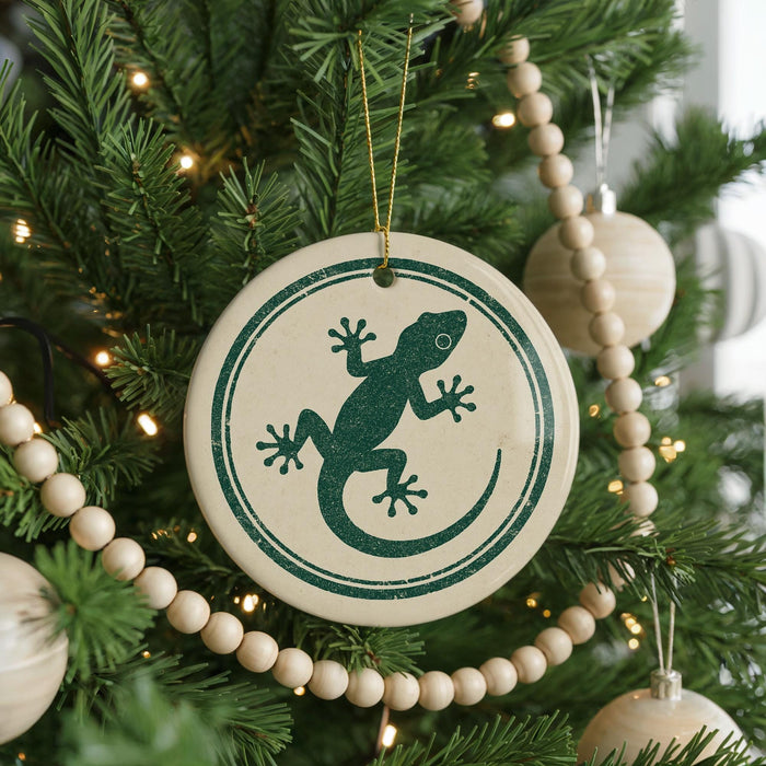 A Christmas tree decorated with ornaments, including a circular ornament with a green lizard design.