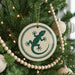 A Christmas tree decorated with ornaments, including a circular ornament with a green lizard design.