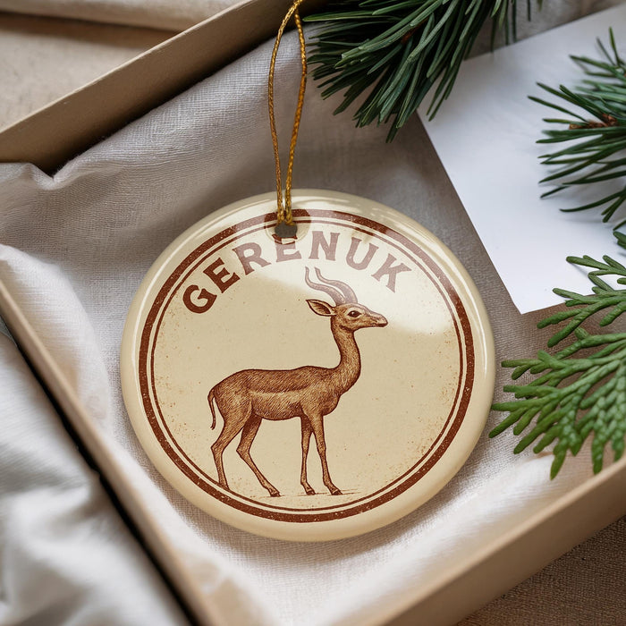 A round ornament with a deer image and the word "Gerenik" written on it, placed in a box with pine branches.