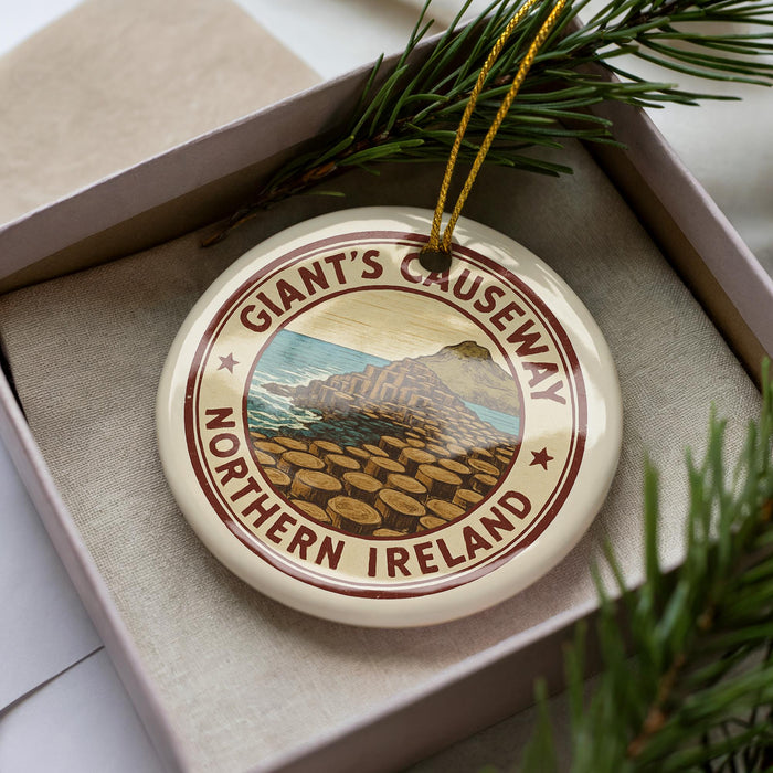A circular ornament with the text "Giant's Causeway Northern Ireland" printed on it, surrounded by pine branches.