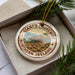 A circular ornament with the text "Giant's Causeway Northern Ireland" printed on it, surrounded by pine branches.