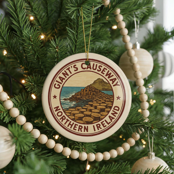 A Christmas tree decorated with ornaments, including a circular ornament with the text "Giant's Causeway Northern Ireland" and a scenic illustration of a coastal landscape.