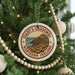 A Christmas tree decorated with ornaments, including a circular ornament with the text "Giant's Causeway Northern Ireland" and a scenic illustration of a coastal landscape.