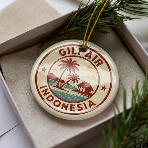 A round ornament with the text "GILT AIR INDONESIA" and a palm tree design, placed in a box with pine branches.