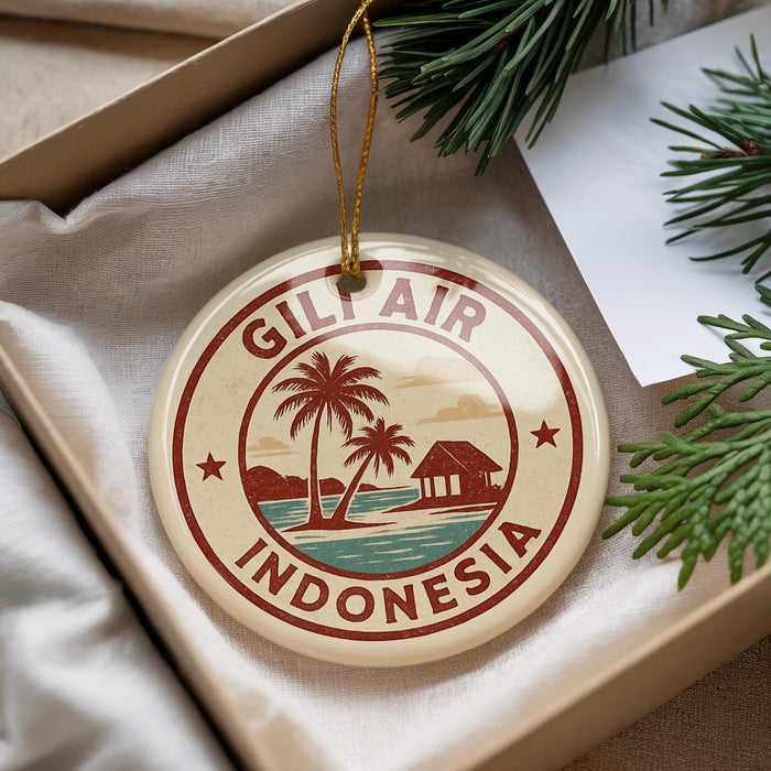 A decorative ornament with the text "GILF AIR INDONESIA" and a palm tree illustration, placed in a box with pine branches.