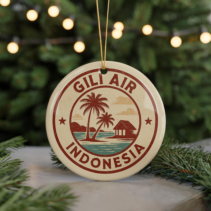 A circular ornament with the text "GILI AIR INDONESIA" and a palm tree design, hanging from a string against a background of Christmas lights and greenery.